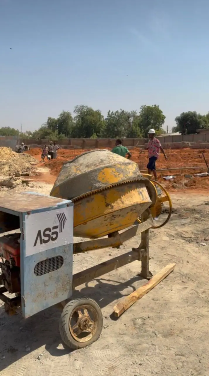 AS5-branded concrete mixer on an active construction site, with workers in hard hats in the background