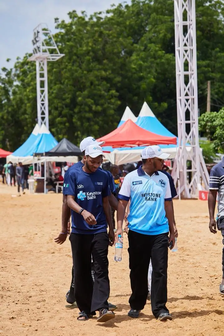 Two players in Keystone Bank team shirts walking past the event marquees