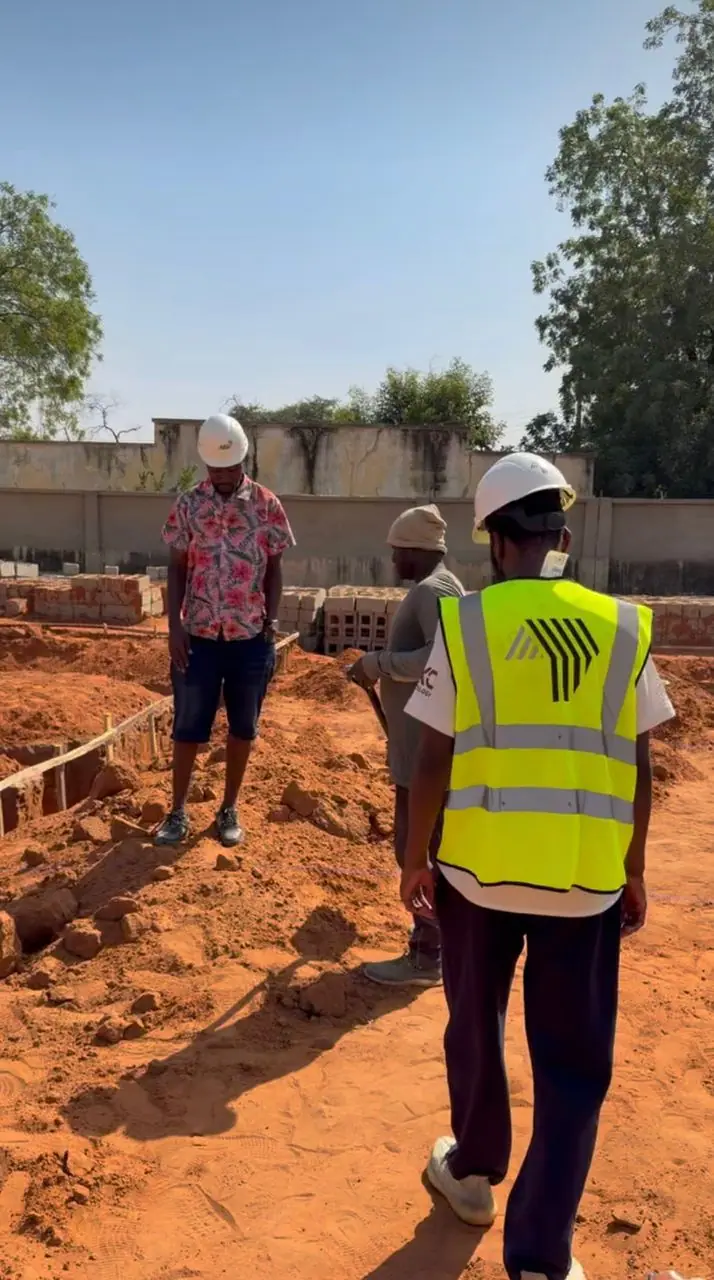 AS5 Group site supervisor in a branded high-visibility vest inspecting foundation works with the project team